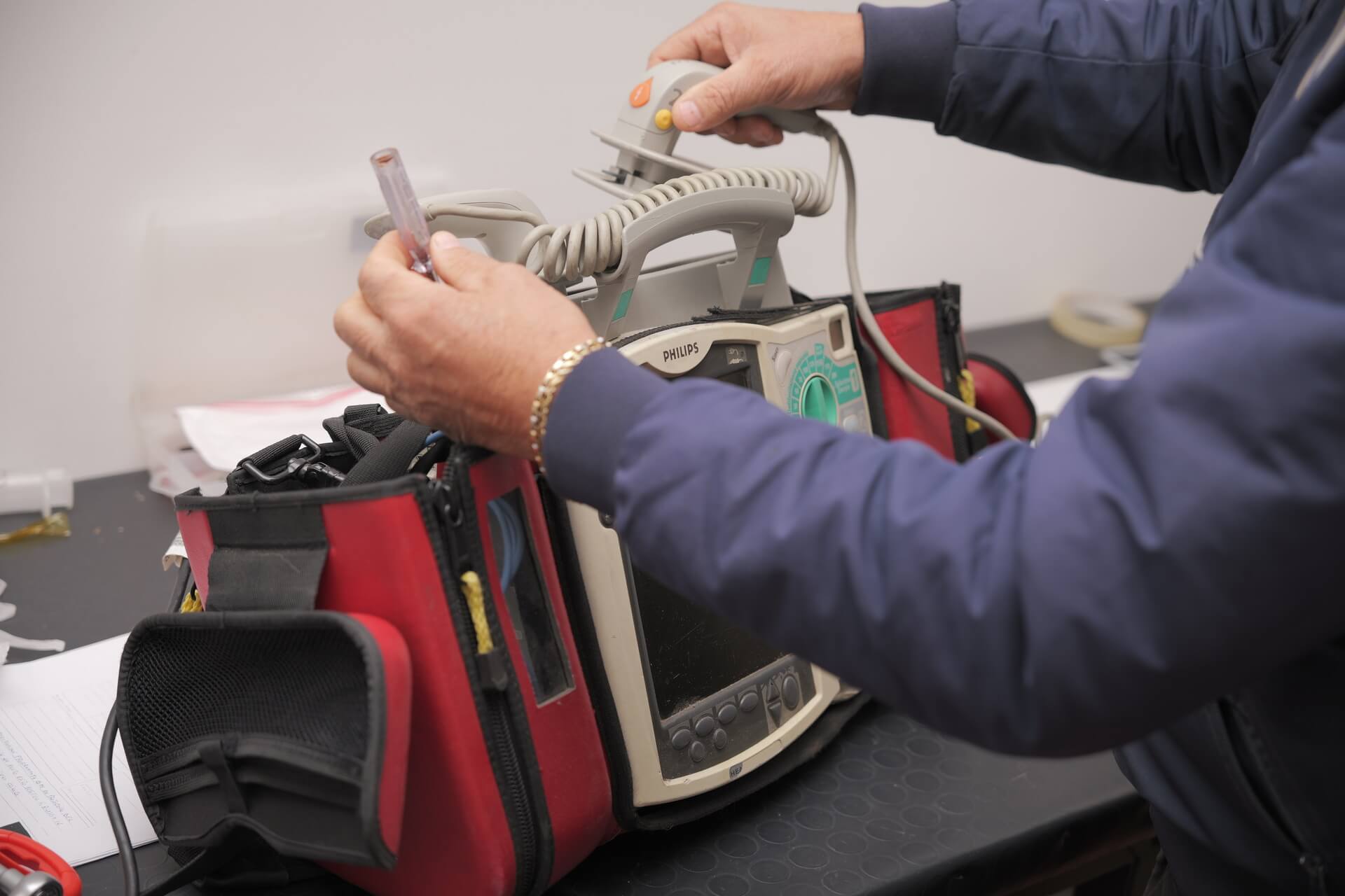 Defibrillatore Philips in borsa rossa, mani che lo maneggiano.